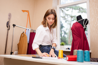 Créatrice de mode en train de travailler sur une tenue dans son atelier, illustrant l'artisanat et le souci du détail de la collection Milanoza pour un style chic et élégant.