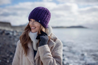 Jeune femme souriante portant un bonnet en tricot violet et une écharpe assortie, parfaits pour l'hiver.