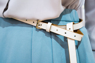 Ceinture blanche élégante sur jupe plissée bleue, accent de style moderne.