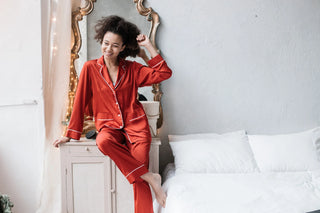 Femme rayonnante dans un pyjama satiné rouge, incarnant le confort et l'élégance des vêtements de nuit.