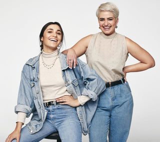 Deux femmes rayonnantes en tenue décontractée en denim sourient à la caméra, symbolisant la convivialité et le style accessible de notre collection de vêtements décontractés.