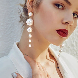 Boucles d'oreilles pendantes élégantes avec grandes et petites perles synthétiques blanches nacrées sur fond clair - Milanoza