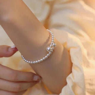 Gros plan d'un bracelet ajustable en perles synthétiques nacrées, montrant le détail des perles et le fermoir discret - Milanoza