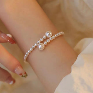 Bracelet en perles synthétiques ajustables couleur crème porté au poignet, idéal pour les occasions élégantes ou quotidiennes - Milanoza